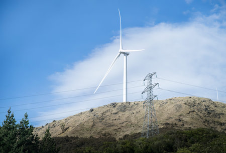 Wind turbine and transmission pylon under a blue sky. Hawke's Bay. New Zealand.