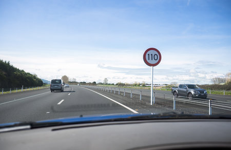 Driving on Waikato Expressway. 110 km/h road speed sign on the road side. Photo taken on the passenger seat. New Zealand.の写真素材