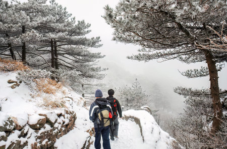 Two men hiking Mount Huangshan in the snow. Anhui province. China.の写真素材