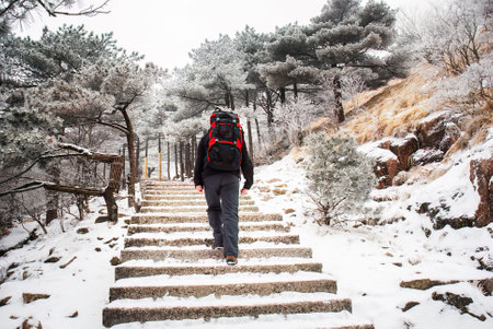 Young man walking on the steps in the snow. Mount Huangshan. Anhui province. China.の写真素材