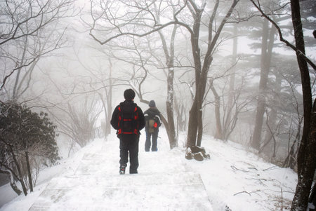 Two backpackers hiking Mount Huangshan in the snow. Anhui province. China.の写真素材