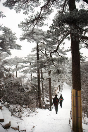 Two men hiking Mount Huangshan in the snow. Vertical format. Anhui province. China.の写真素材