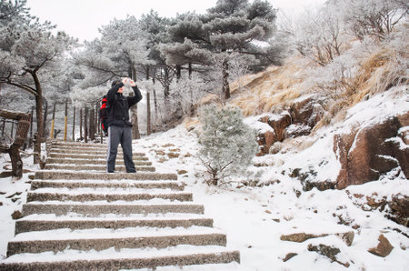 Young man taking photos in the snow. Mount Huangshan. Anhui province. China.の写真素材