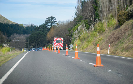 Orange traffic cones on the road. Cars stopped by the work truck. Roadwork in Hawkeâs Bay. New Zealand.の写真素材