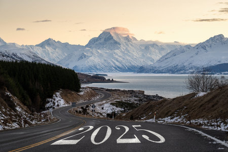 New Year 2025. Text 2025 written on Mt Cook road. Snow-capped Mt Cook in the distance, South Island.