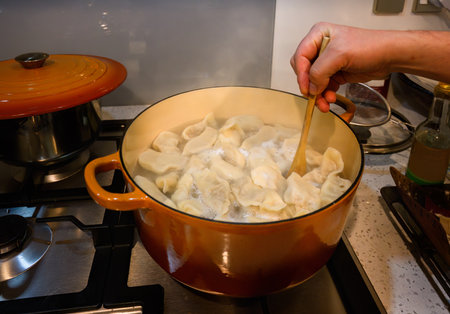 Hands stirring dumplings in the boiling water in the pot. Home cooking.の写真素材