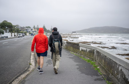 Two people walking on Plimmerton beach on a cold windy day. Wellington.の写真素材