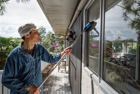 Man cleaning windows using a brush. Rental house maintenance work. Auckland.の写真素材
