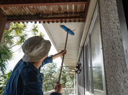 Man cleaning soffit using a brush. Rental house maintenance work. Auckland.の写真素材