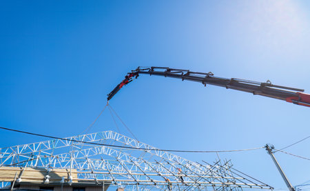 Low angle view of a construction crane and scaffolding. Unrecognizable workers on the scaffolding over a residential building. Auckland.の写真素材