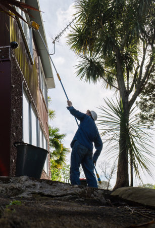 Man cleaning windows using a long brush. Home maintenance work. Vertical format.の写真素材