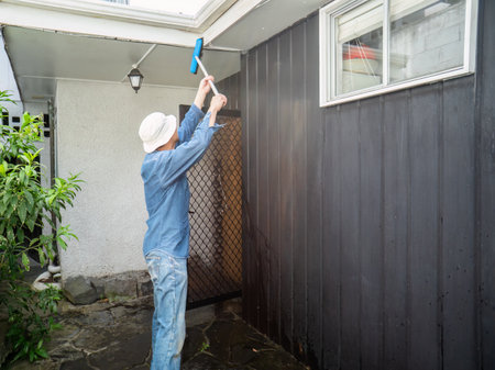 Man cleaning fascia using a brush. Home maintenance work. Auckland.の写真素材
