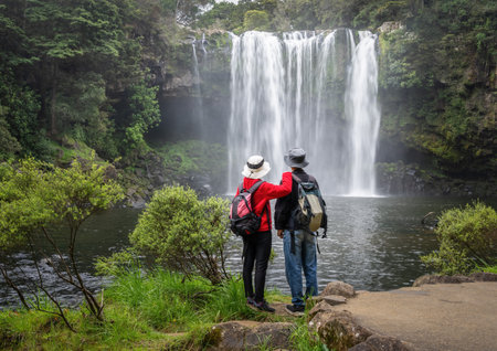 Couple enjoying the view of Rainbow Falls on the Kerikeri river. Northland. New Zealand.の写真素材