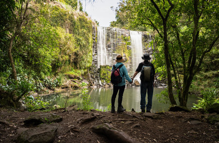 Couple holding hands and enjoying the view of Te Wairere Waterfall. Bay of Islands.の写真素材