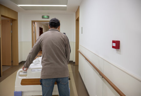 Man pushing a patient lying in bed in a corridor at the hospital.の写真素材