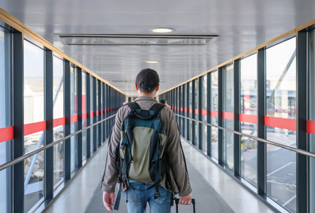 Man walking in the airport passenger boarding bridge. Unrecognisable passagers in the background.の写真素材