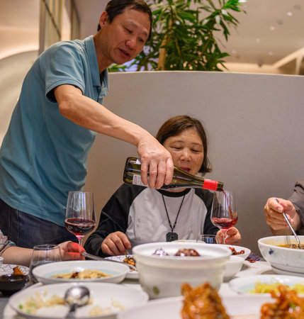 Man pouring red wine to the wine glasses at the restaurant. Woman smiling and looking at the wine glass.の写真素材