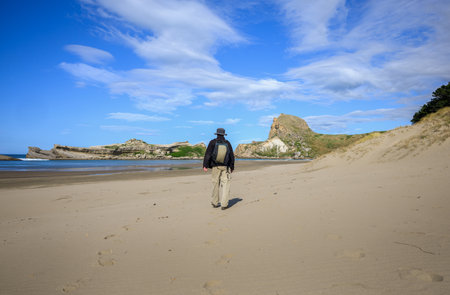 Man walking on the beach towards Castle Rock. Castlepoint. Wairarapa. New Zealand.の写真素材