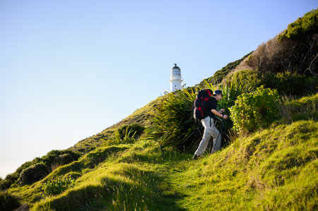 Backpacker hiking Cape Brett Track. Cape Brett Lighthouse in the distance. Bay of Islands.の写真素材