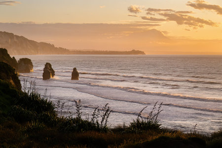 Three Sisters at sunset. Mount Taranaki peeking through the cloud. Tongaporutu. Taranaki. New...