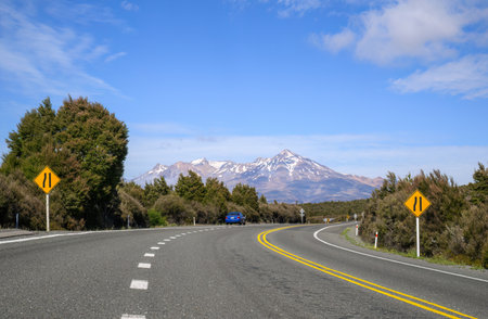Road narrows on left road sign on Desert road. Mount Ruapehu in the distance. New Zealand.の写真素材