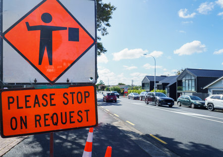 Please Stop on Request road sign by the road. Cars travelling on the road. Roadworks in Auckland.の写真素材