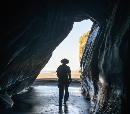 Man in silhouette walking in the cave at Three Sisters. Tongaporutu. Taranaki. New Zealand.の写真素材