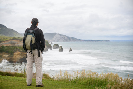 Man standing on clifftop and looking at the views of Three Sisters rock formation. Tongaporutu. Taranaki. New Zealand.の写真素材