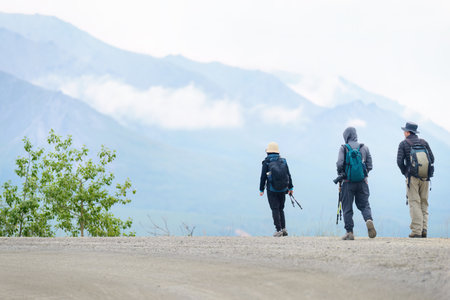 Three people hiking Denali National Park and Preserve. Cloud drifting around the high mountains. Alaska. USA.の写真素材