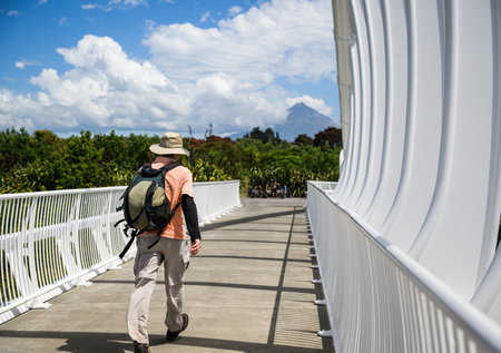 Male tourist walking on the Te Rewa Rewa Bridge. Mt Taranaki in the distance. New Plymouth.の写真素材