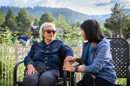 Smiling elderly woman and middle aged daughter together at home in the backyard.の写真素材