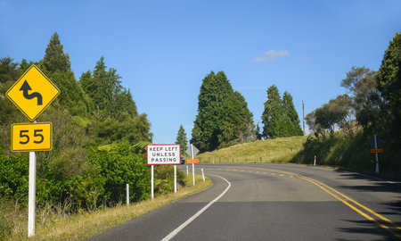 Keep Left Unless Passing road sign on a winding road. North Island. New Zealand.の写真素材