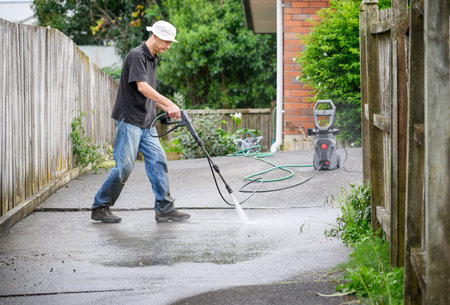 Man washing concrete driveway using a pressure washer.の写真素材