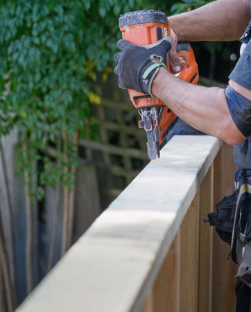 Hands of a builder working on fence using a nail gun construction tool. Vertical format.の写真素材