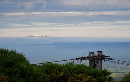 Mt Ruapehu at sunset, seen from the slope of Mt Taranaki. Power cables and post in the foreground. Taranaki.の写真素材