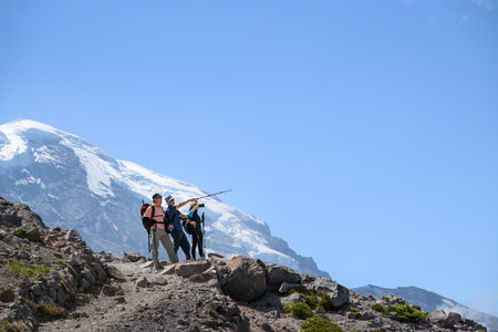 Three backpackers hiking the Sunrise Trail in summer. Mount Rainier in the background. Mt Rainier National Park. Washington State.の写真素材