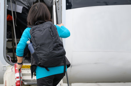Woman climbing up the stairs and boarding a small airplane. CAUTION sign printed on the top of steps. Alaska. USA.の写真素材