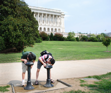 Tourists drink water from a water fountain outside Capitol Hill on a hot summer day. Washington D.C.の写真素材