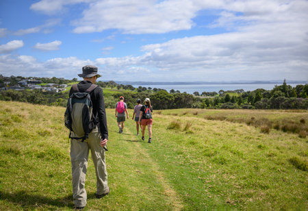 Group of people walking on green hill at Shakespear Regional Park. Auckland.の写真素材