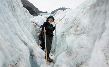Woman walking on Franz Josef Glacier. People wearing ice crampons and walking on ice. South Island. New Zealand.の写真素材