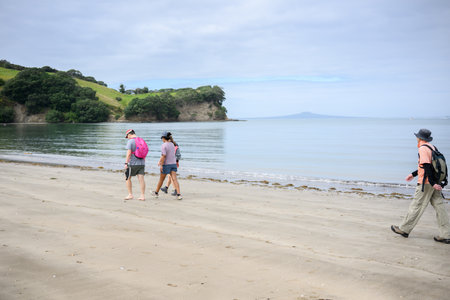 People walking on the beach at Shakespear Regional Park. Rangitoto Island in the distance. Auckland.の写真素材