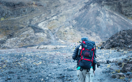 Backpacker hiking on volcanic loose scree at Tongariro Alpine crossing, Unrecognizable hikers in the...