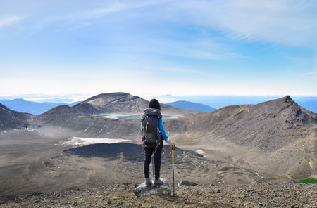 Woman looking at the views of Blue Lake and Emerald lakes. Mt Taranaki in the far distance. Tongariro Alpine Crossing, Tongariro National Park. New Zealand.の写真素材