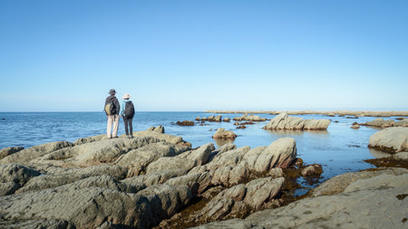 Couple holding hands and standing on the rocky beach. Kaikoura. South Island. New Zealand.の写真素材