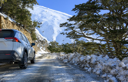 Car driving on winding mountain road with rear tire snow chains. Twizel. South Island.の写真素材