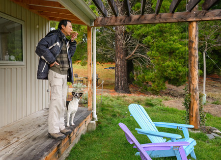 Man eating toast with dog looking on. South Island. New Zealand.の写真素材