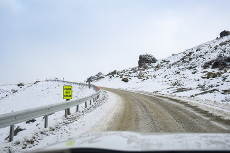 CHAIN BAY AHEAD road sign on a frozen snow mountain road. Wanaka. Otago Region. South Island.の写真素材