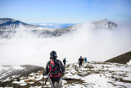 Man hiking Tongariro Alpine Crossing in winter. Blue Lake in the distance; Unrecognizable hikers...