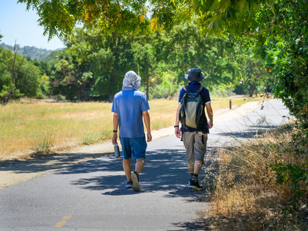 Two men walking on the suburban road in the hot summer. San Jose. California.の写真素材