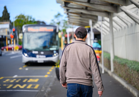 Man walking towards bus at bus stop on a city street. Auckland.